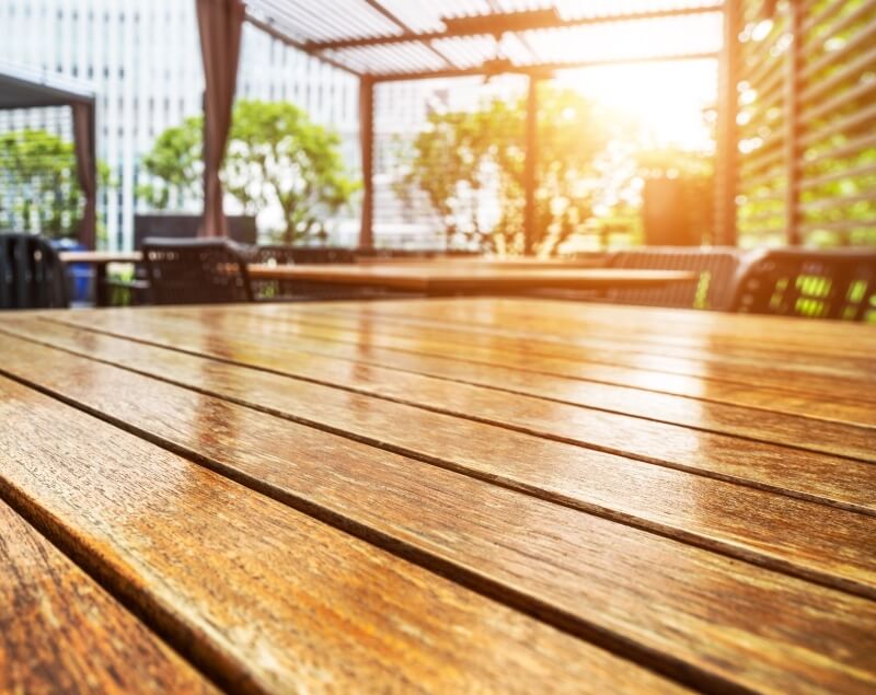 Stół na tarasie, efektownie zakonserwowany dzięki lazurowaniu drewna.