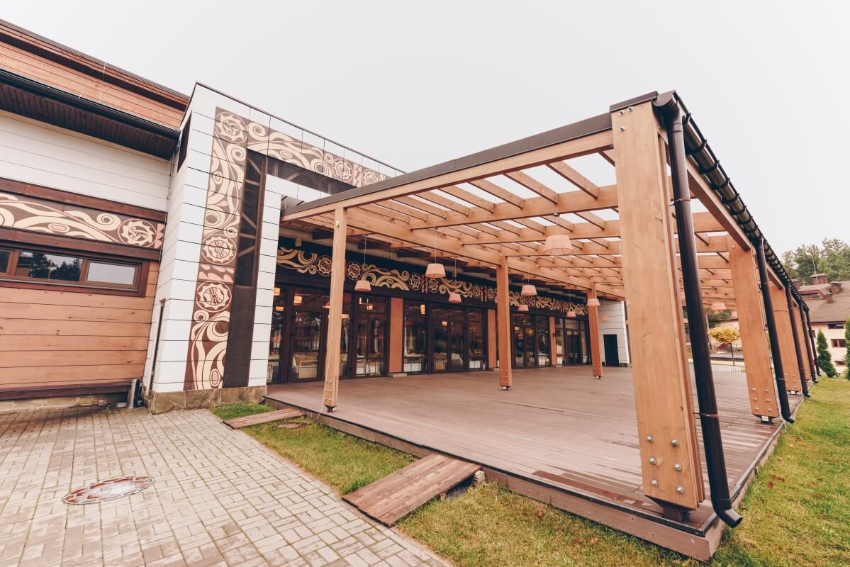 Nowoczesny budynek z ozdobnymi panelami i przestronny taras drewniany.